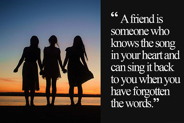 Three friends standing together with friendship saying card