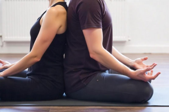 A couple seated in a yoga pose, showcasing their bond